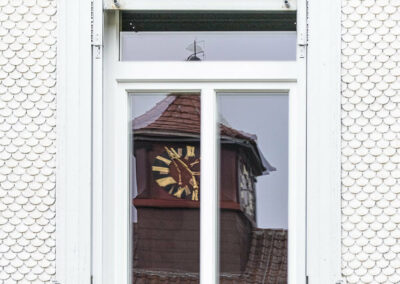 Turmhur spiegelt sich in einem alten Fenster