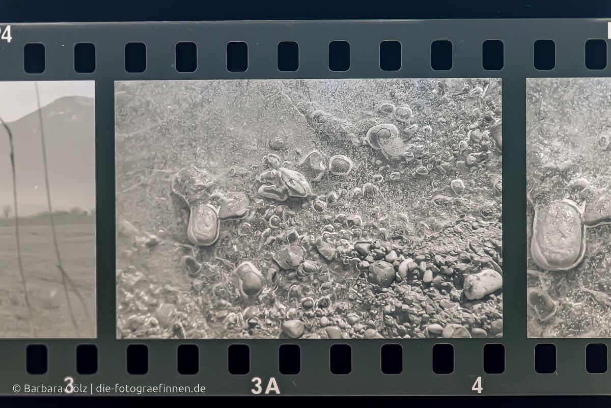 Foto eines schwarz/weiß Films, der Steine in gefrorenem Wasser zeigt